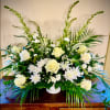 Low white and cream flower arrangement with roses and mums accented by tall palm fronds in a white bowl