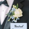 White rose and blue flower boutonniere pinned to a black tuxedo jacket