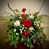 Low arrangement of red roses, red and white carnations, white mums, and berries with cascading evergreen branches