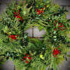 Evergreen wreath with glossy foliage and clusters of bright red berries on a stone surface