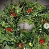 Evergreen wreath with glossy foliage and clusters of red berries on a stone surface