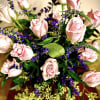Bouquet of light pink roses with purple accent flowers in a clear vase