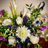 Mixed arrangement of white roses, calla lilies and purple and blue blooms in a vase