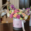 Pink and peach roses in a round gift box with a ribbon