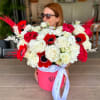 Bouquet of red and white roses with red anemones in a pink hatbox