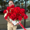 Large bouquet of red roses wrapped in white paper with a red ribbon