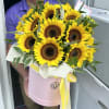 Bouquet of yellow sunflowers in a pink hatbox with a yellow ribbon