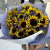 Bouquet of sunflowers and purple daisies wrapped in lavender paper