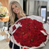 Woman holding a large bouquet of red roses wrapped in white paper