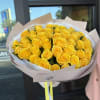 Bouquet of yellow roses wrapped in pale paper