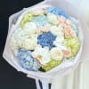 Pastel bouquet of hydrangeas, roses, and white orchids wrapped in pink paper