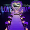 Purple floral wedding aisle with heart arch, candles, and lit LOVE sign