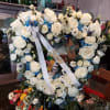 Heart-shaped wreath of white roses with blue flowers and a white ribbon