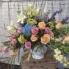 Large mixed bouquet with roses, lilies, hydrangeas, and delphinium in a white vase