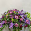 Large purple and pink floral spray with ribbon on a stand