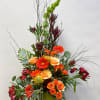 Tall floral arrangement with orange roses, gerbera daisies, and burgundy blooms in a green vase