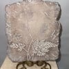 Textured stone plaque with an etched floral stem design on a metal stand