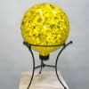 Yellow glass orb on a black metal stand
