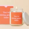 Lit candle in a glass jar beside an orange box