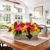 Bright mixed flower arrangement in a wooden box on a dining table