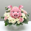 Pink pig-shaped floral arrangement in a white pedestal vase with roses