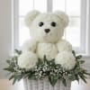 White teddy bear made of flowers in a wicker basket with greenery