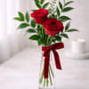 Two red roses in a clear glass vase with a red ribbon