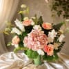 Soft blush hydrangea crowns this romantic bouquet, framed by large pink roses