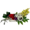 Arrangement of red roses with pale orchids in a white container