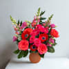 Pink and red mixed bouquet in a round orange vase