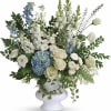 White and blue floral arrangement in a white urn vase