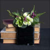 Green and white flowers in a black ribbon wrap on stacked books