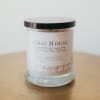 A glass jar candle with a black lid and white label