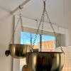 Two gold hanging planters suspended from chains indoors
