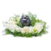 Cremation urn encircled by white roses and hydrangeas with green accents