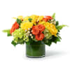 Low arrangement of yellow orchids and roses with orange roses in a green-lined glass cylinder vase