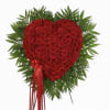 Heart-shaped cluster of red roses framed by radiating green foliage with long red ribbons