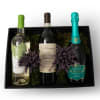Gift box with three assorted wine bottles nestled in moss with purple dried sprigs