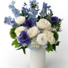 White and blue flower arrangement with roses and anemones in a tall white cylinder vase
