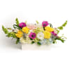 Low rectangular arrangement of yellow roses, pink anemones and mixed blooms in a white vase
