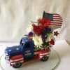 Floral arrangement in a patriotic truck-shaped container with an American flag topper