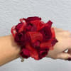 Red rose wrist corsage with sheer ribbon on a person's wrist