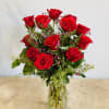 Red roses arranged in a clear glass vase with small pink filler flowers