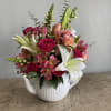 Pink and white mixed flower arrangement in a white teapot vase