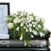 White floral arrangement on a black casket with calla lilies and roses