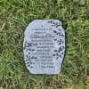 Memorial stone with engraved text lying in grass