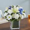 White and blue mixed bouquet in a square glass vase