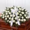 White rose funeral spray with a white ribbon on a casket