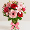 Pink and red flower bouquet in a glass vase with a pink ribbon