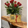Red roses arranged in a vase with a gold Godiva gift box